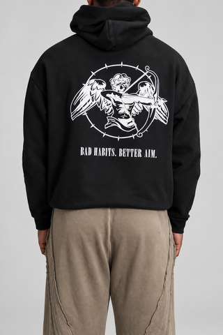 Back close-up studio view of the Black Bad Habits Hoodie, showing the cupid archer graphic and BAD HABITS. BETTER AIM. text.