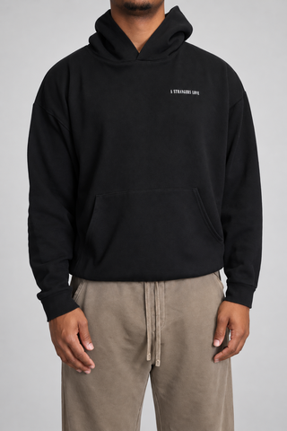 Front close-up studio view of the Black Bad Habits Hoodie, showing the small A STRANGERS LOVE chest print, hood shape, and kangaroo pocket.
