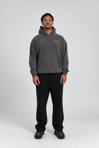 Front full-body studio view of a model wearing the Grey Bad Habits Hoodie with black pants and black sneakers.