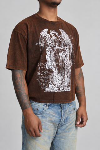 Close-up of the brown washed Guardian Cropped T-Shirt on model, showing the angel graphic, mineral wash, fabric texture, collar, sleeves, and cropped hem.