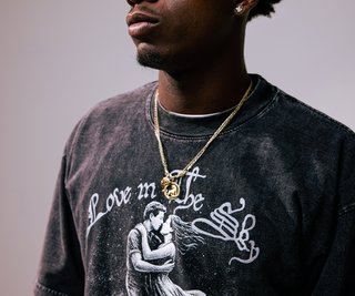 Person wearing a black t-shirt with a graphic design and gold necklace.