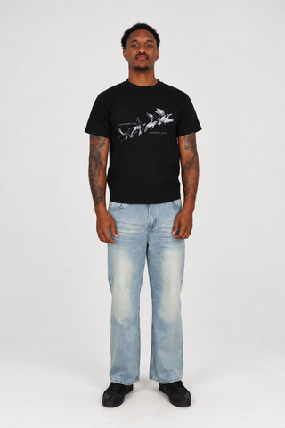 Model wearing the black Somewhere Better T-Shirt and light blue Sun Fade Raw Hem Jeans, full-body front studio view.