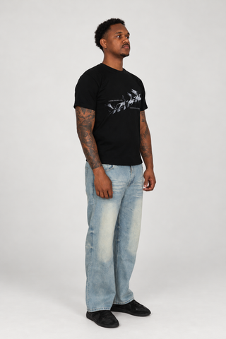 Model wearing the black Somewhere Better T-Shirt and light blue Sun Fade Raw Hem Jeans, full-body right three-quarter studio view.