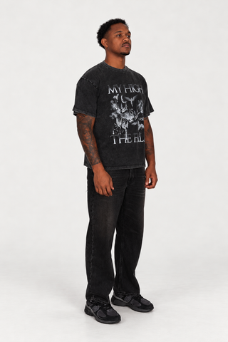 Right-facing three-quarter view of a model wearing The Fall T-Shirt in Black Washed, showing the graphic and relaxed fit.
