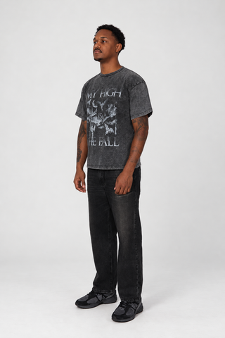 Left-facing three-quarter view of a model wearing The Fall T-Shirt in Grey Washed with black jeans and dark sneakers.